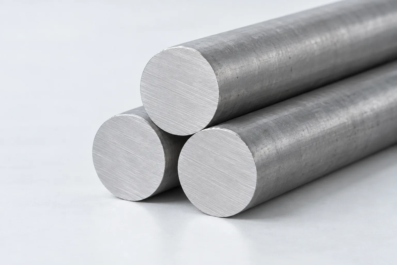 Three raw stainless round bars are stacked with their square-cut ends facing the camera.